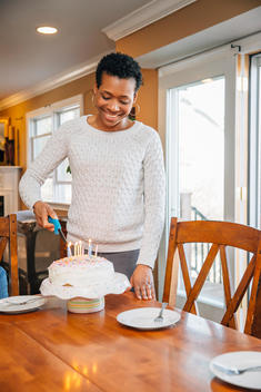 Black woman lighting candles on birthday cake