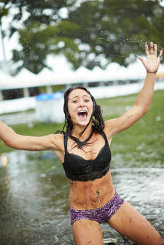 A woman splashing in a puddle at a music festival