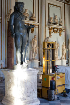 Black marble statue of Baby Hercules and forklift at Museum Capitolini in Rome.
