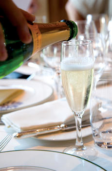 A glass of Verve Clique Champagne is being poured at a formal dinner table in Chateau Bretesch , Britanny