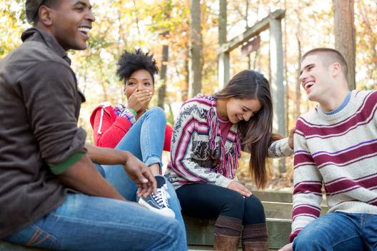 Group of young adults laughing and having a good time outdoors in fall scenery