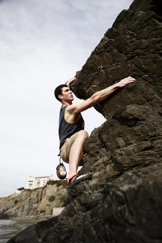 An athletic man rock climbing at the beach