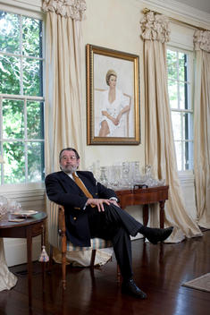 Portrait Of A Man Dressed In A Suit Sitting On A Chair In His Living Room