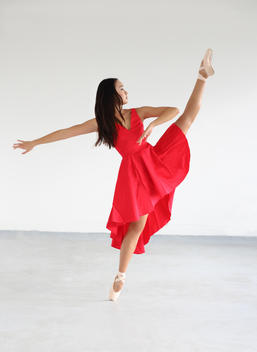 Dancer in red dress kicking into air