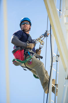 Caucasian worker harnessed to cell tower