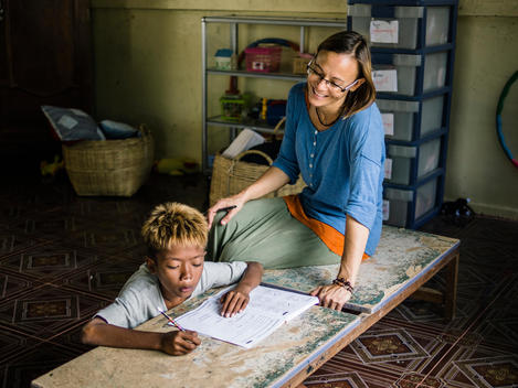 A teacher watchs a boy do his schoolwork at The Wat Opot Community, an orphanage for children affected by HIV and AIDS, near Chambak, Cambodia, outside Phnom Penh.