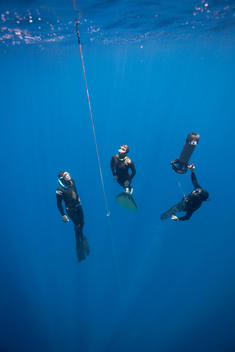 Free diver with safety divers ascending to surface
