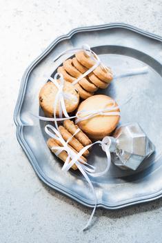 Overhead view of shortbread cookies tied with white ribbon on silver serving dish
