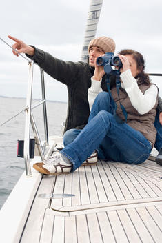 Germany, Baltic Sea, L?becker Bucht, Young couple on boat, woman looking through binoculars