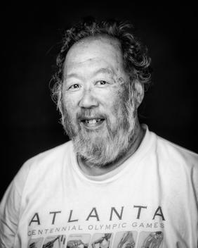 Black and white portrait of elderly man with 96 olympics t-shirt smiling