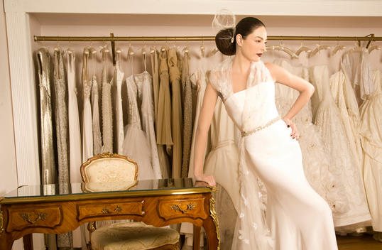 Woman leaning on desk in bridal dress store