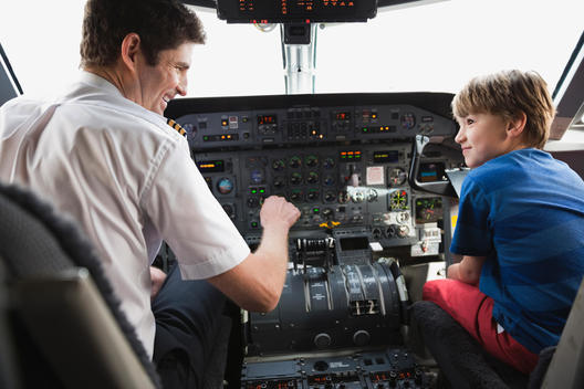 Boy sitting with pilot in airplane cockpit
