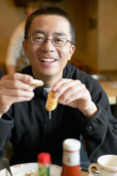 Asian man eating in restaurant