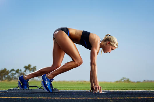 Fit woman in starting blocks of race track