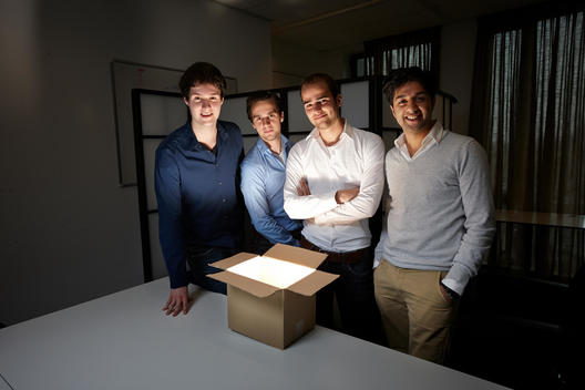four young entrepreneurs of startup with light emitting from box in front of them