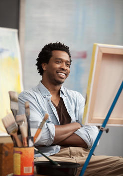 Smiling Black artist looking at easel
