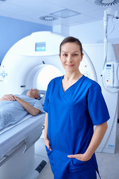 Radiographer standing in front of man going into CT scanner