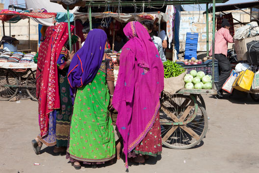 Indian women wearing sari and shopping at a vegetable market stall