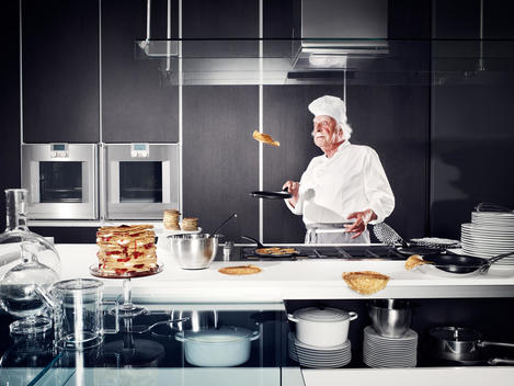 A weird chef making pancakes in a designer kitchen.