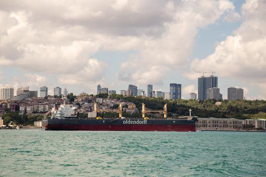 Commercial vessel loaded with goods in its containers sailing through Bosphorus Strait passing the city of Istanbul than to the Black Sea.