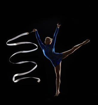 Athletic Olympic rhythmic gymnast creating waves with ribbon