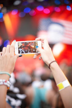 A person photographing a concert with their smartphone