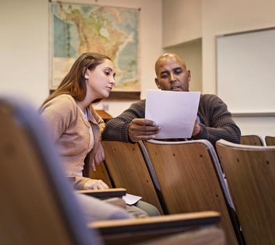 Professor and student reviewing essay in lecture hall