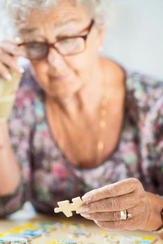 Senior woman solving jigsaw puzzle at table in nursing home