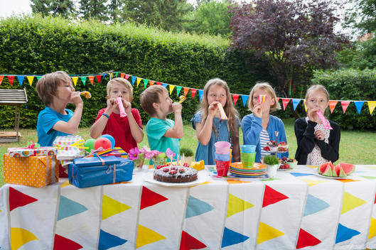 Children using party blowers on a birthday party