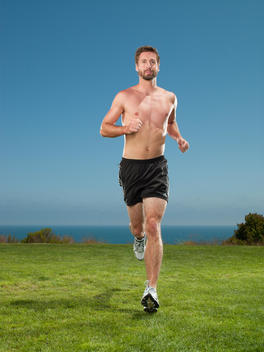 An athletic man is jogging on a seaside cliff