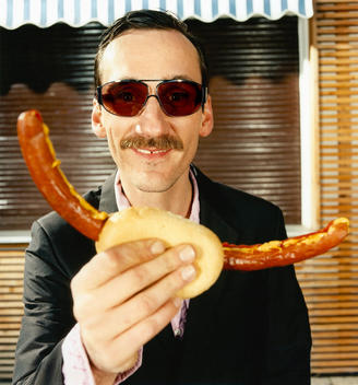 Portrait Of Man Holding Sausage And Smiling