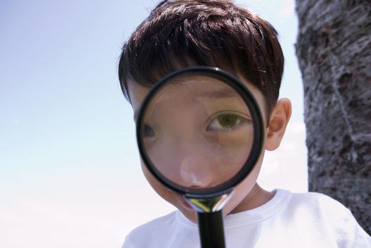 Boy looking through magnifying glass, close-up