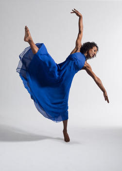 Black female dancer in blue dress against white background