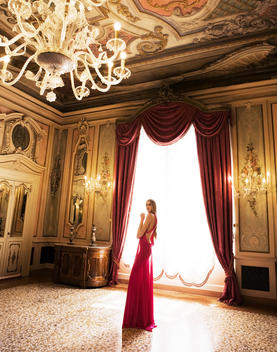 A model in a old palazzo standing with a floor length dress on.