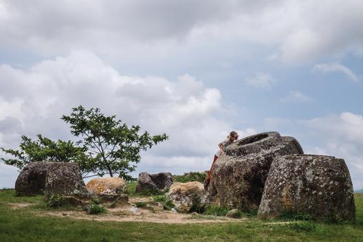 Checking out what might be left inside the largest Jar on the Plain of Jars site near Phonsavan, Laos. 1000s of stone jars are scattered through the landscape. Scientists are not sure what they were used for but some suggest it\'s an elaborate burial site.