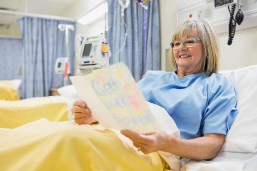 Senior woman reading Get Well card in hospital