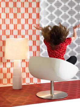 A Young Girl Sitting On A Modern Chair With Her Hands In The Air