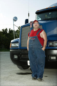 American trucker stands in front of his truck.