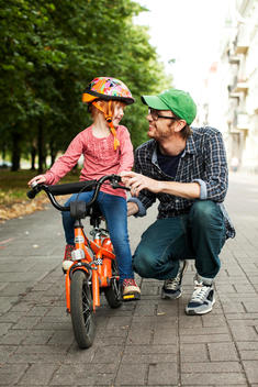 Happy man looking at daughter sitting on bicycle smiling at him