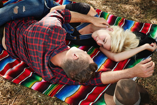 Caucasian couple laying on blanket in park