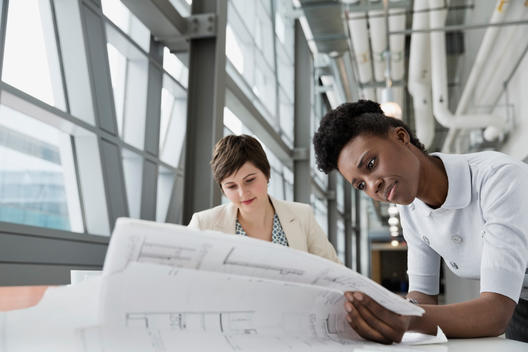 Businesswomen looking at blueprint in office building