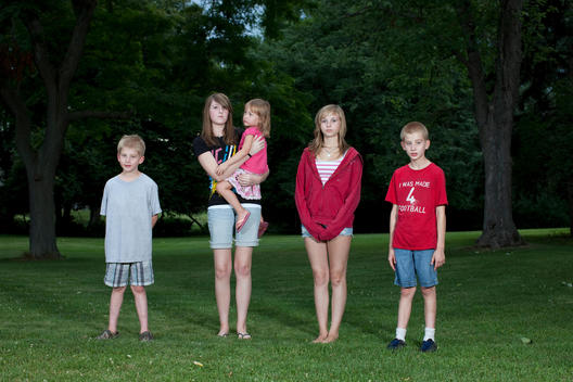 A Group Of Cousins Pose For A Family Portrait At A Barbecue.
