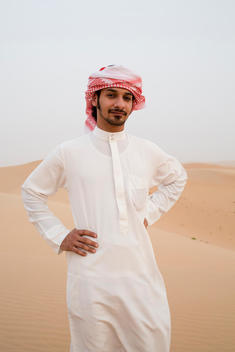 portrait of man wearing traditional Arab clothing standing in desert