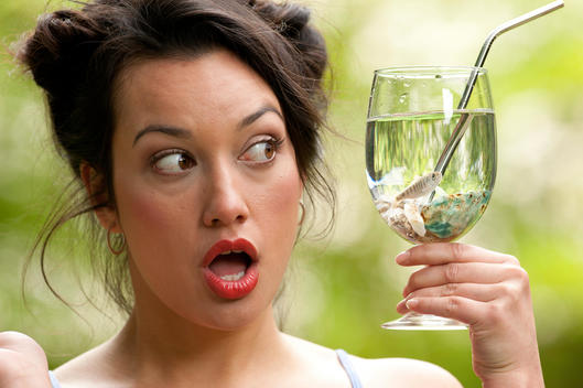 Young woman surprised to find a fish in her water glass