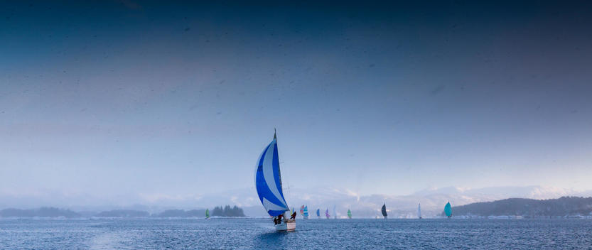 Yacht sailing in a race in the Bergen fjord, Norway, during winter, with spinnaker in action.