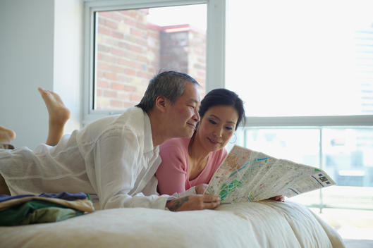 Asian couple looking at map in bedroom