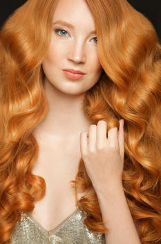 Close up of red haired Young Woman holding lock of hair