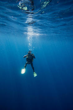 Scuba diver descending into deep blue sea