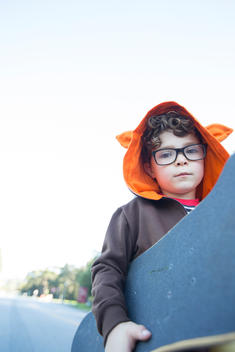 5 year old caucasian boy with skateboard under arm, looking at the camera.