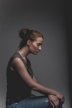 androgynous female, with red hair pulled back. Wearing grey t-shirt with sleeves rolled up. Looking away from camera. profile portrait.